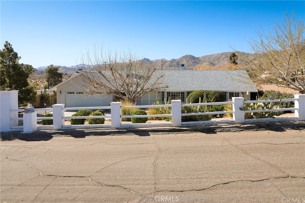 61849 Alta Mesa Dr, Joshua Tree, CA 92252 - single story home with a fenced front yard, a mountain view, an attached garage, and a chimney