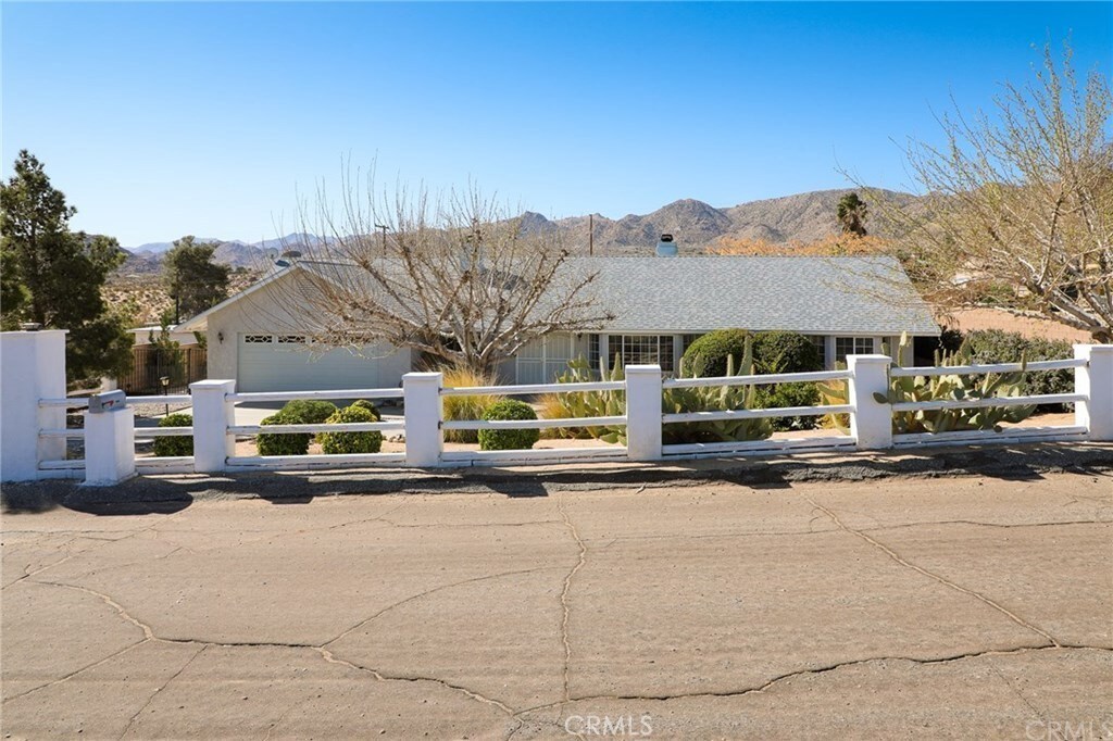 61849 Alta Mesa Dr, Joshua Tree, CA 92252 - single story home featuring a fenced front yard, a mountain view, a garage, and a chimney