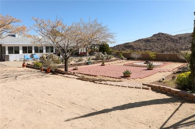 61849 Alta Mesa Dr, Joshua Tree, CA 92252 - fenced backyard with a mountain view, a patio, and a sunroom