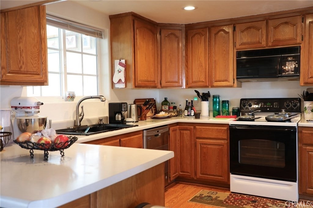 61849 Alta Mesa Dr, Joshua Tree, CA 92252 - kitchen with black microwave, range with electric stovetop, brown cabinets, light countertops, and recessed lighting