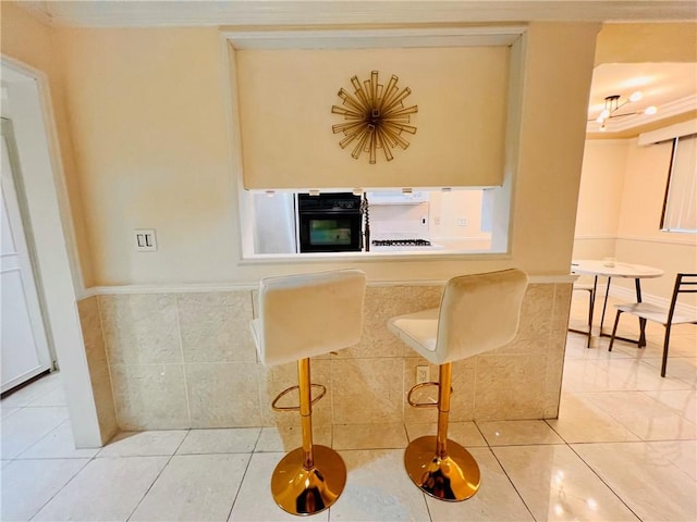 28004 Western Ave S Unit 121, San Pedro, CA 90732 - kitchen with black oven, light tile patterned flooring, wainscoting, a kitchen bar, and extractor fan