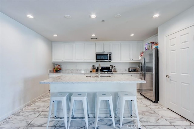 28420 Abbey Ln, Menifee, CA 92585 - kitchen with stainless steel appliances, light marble finish floors, white cabinets, recessed lighting, and a kitchen breakfast bar