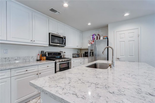 28420 Abbey Ln, Menifee, CA 92585 - kitchen featuring appliances with stainless steel finishes, white cabinetry, recessed lighting, and light stone countertops