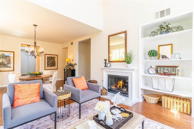 3867 Taconite Rd, San Bernardino, CA 92407 - living area featuring wood finished floors, a chandelier, a glass covered fireplace, and built in shelves