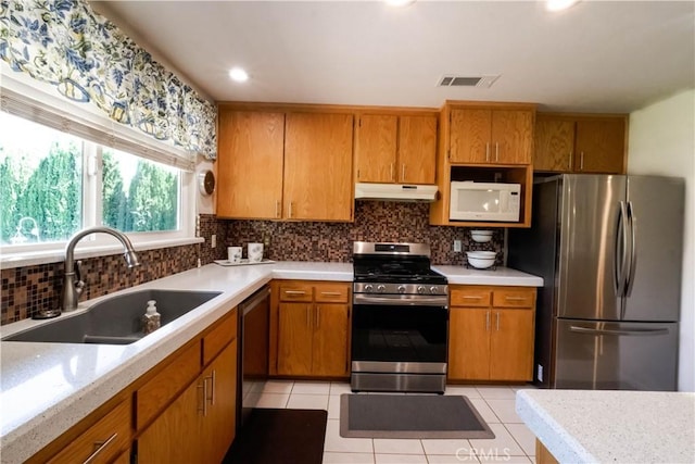 3376 Hackamore Ln, Chico, CA 95973 - kitchen with appliances with stainless steel finishes, under cabinet range hood, light countertops, backsplash, and brown cabinets