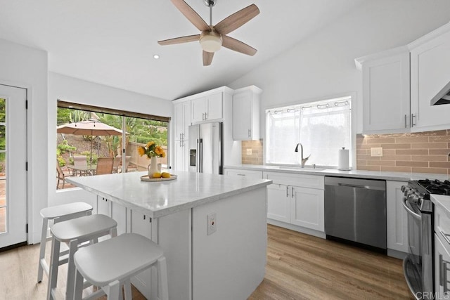 1642 Marbella Dr, Vista, CA 92081 - kitchen with stainless steel appliances, vaulted ceiling, a kitchen island, backsplash, and light wood-style flooring