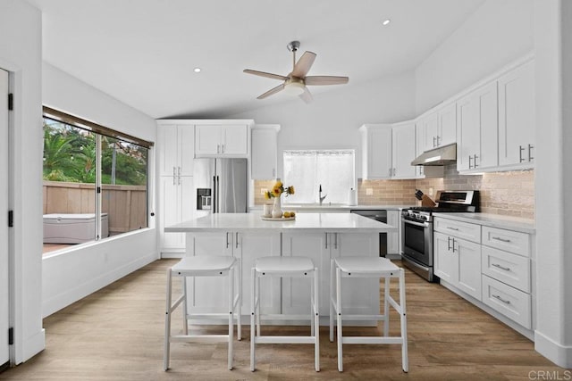 1642 Marbella Dr, Vista, CA 92081 - kitchen featuring stainless steel appliances, under cabinet range hood, backsplash, a breakfast bar, and a kitchen island