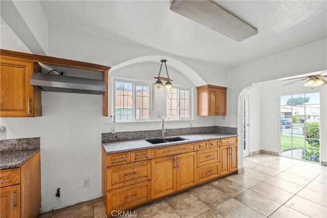 621 S Burris Ave, Compton, CA 90221 - kitchen with brown cabinets, wall chimney range hood, arched walkways, and decorative light fixtures