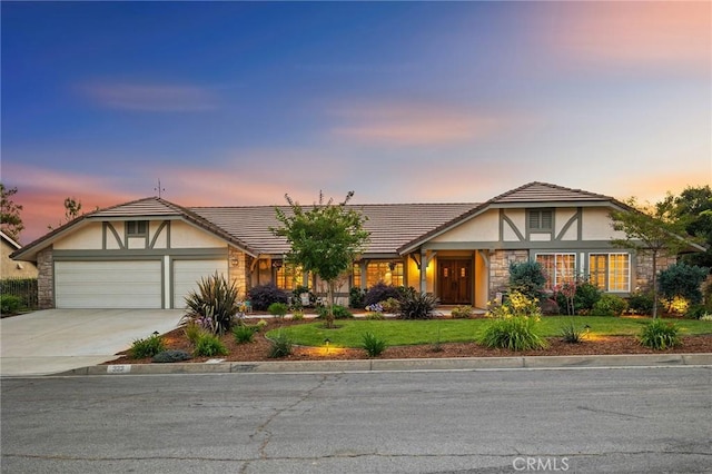 323 N Hacienda Ave, Glendora, CA 91741 - tudor house featuring stucco siding, driveway, an attached garage, stone siding, and a yard