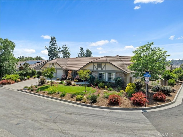 323 N Hacienda Ave, Glendora, CA 91741 - tudor house with stucco siding, a tiled roof, driveway, stone siding, and an attached garage