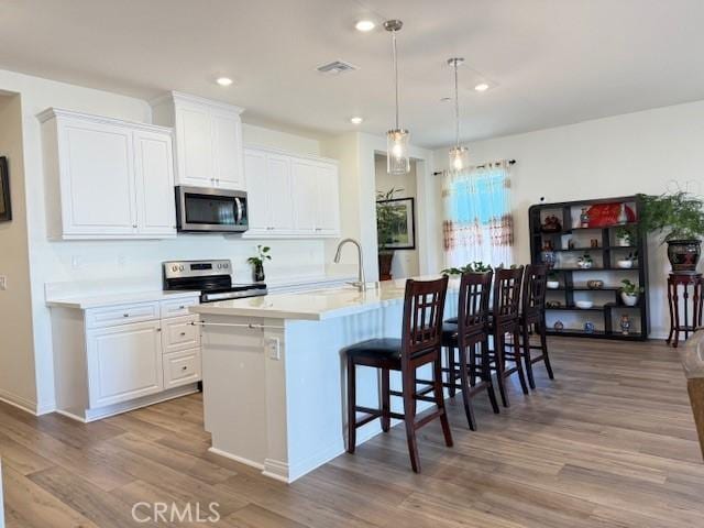 7676 Nectarsweet Dr, Riverside, CA 92507 - kitchen with stainless steel appliances, light wood-style floors, light countertops, a kitchen bar, and recessed lighting