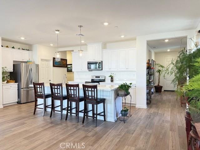 7676 Nectarsweet Dr, Riverside, CA 92507 - kitchen featuring appliances with stainless steel finishes, light wood-style flooring, light countertops, white cabinets, and recessed lighting
