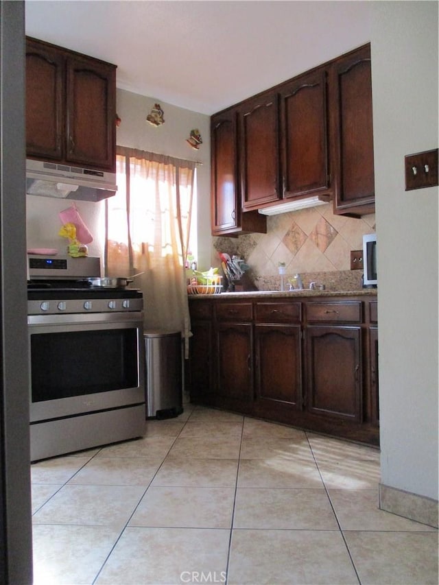 2713 E Monroe St, Long Beach, CA 90810 - kitchen featuring gas stove, under cabinet range hood, decorative backsplash, dark brown cabinetry, and light tile patterned floors