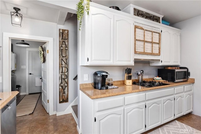 402 E St, Orland, CA 95963 - kitchen featuring stainless steel microwave, gas water heater, black gas stovetop, and white cabinets