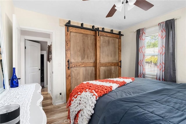402 E St, Orland, CA 95963 - bedroom featuring light wood-type flooring, a barn door, ceiling fan, and a closet