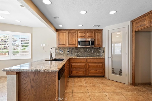 58960 Delano Trl, Yucca Valley, CA 92284 - kitchen featuring stainless steel appliances, brown cabinetry, light stone counters, healthy amount of natural light, and recessed lighting