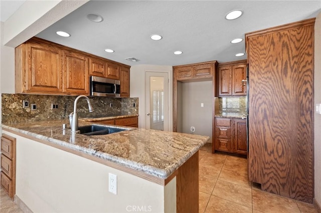 58960 Delano Trl, Yucca Valley, CA 92284 - kitchen featuring stainless steel microwave, a peninsula, light stone countertops, recessed lighting, and backsplash