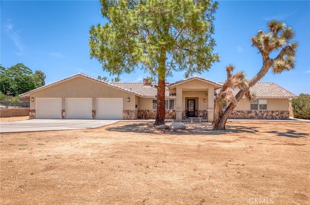 58960 Delano Trl, Yucca Valley, CA 92284 - view of front of house featuring an attached garage, stone siding, stucco siding, and driveway