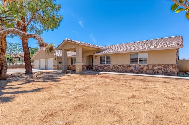 58960 Delano Trl, Yucca Valley, CA 92284 - view of front facade featuring stucco siding, a tiled roof, a garage, and stone siding