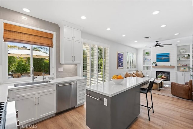 27811 Bloomfield Ct, Valencia, CA 91354 - kitchen with dishwasher, light wood-style flooring, a large fireplace, a kitchen breakfast bar, and recessed lighting