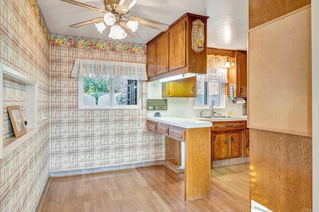 1106 Dawnridge Ave, El Cajon, CA 92021 - kitchen with wallpapered walls, brown cabinets, light countertops, ceiling fan, and light wood-style flooring
