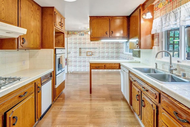 1106 Dawnridge Ave, El Cajon, CA 92021 - kitchen featuring brown cabinets, a warming drawer, light wood-style floors, under cabinet range hood, and white appliances