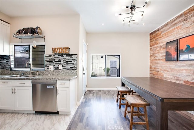 10105 S Main St, Los Angeles, CA 90003 - kitchen featuring stainless steel dishwasher, stone countertops, white cabinetry, wooden walls, and tasteful backsplash