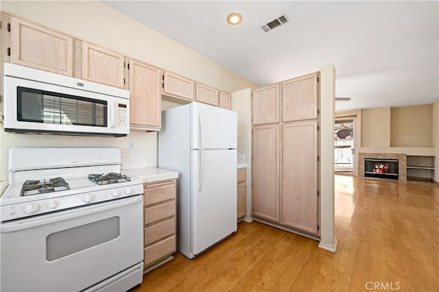 27812 Ruggie Rd, Menifee, CA 92585 - kitchen with white appliances, light brown cabinets, light wood finished floors, tile countertops, and a tile fireplace