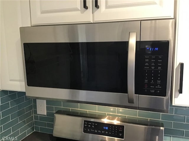 9144 Oakleaf Ct, Hesperia, CA 92344 - kitchen view of stainless steel microwave, white cabinetry, and decorative backsplash