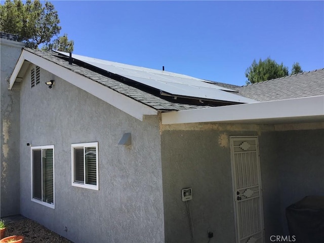9144 Oakleaf Ct, Hesperia, CA 92344 - doorway to property with roof mounted solar panels, roof with shingles, and stucco siding