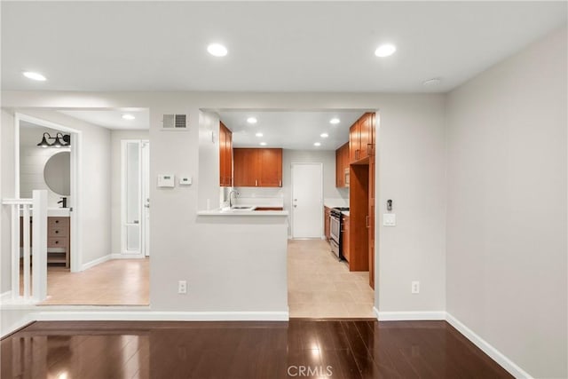 22271 Caminito Danubo, Laguna Hills, CA 92653 - kitchen with recessed lighting, stainless steel range with gas cooktop, brown cabinets, light countertops, and light wood finished floors