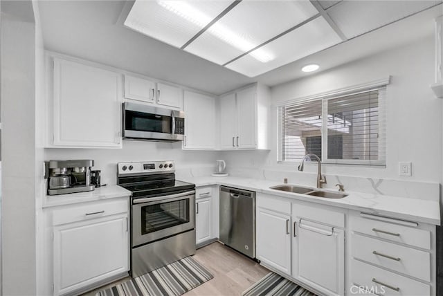 5510 Paseo Del Lago W Unit 2D, Laguna Woods, CA 92637 - kitchen with stainless steel appliances, white cabinets, light wood-style floors, and light stone countertops