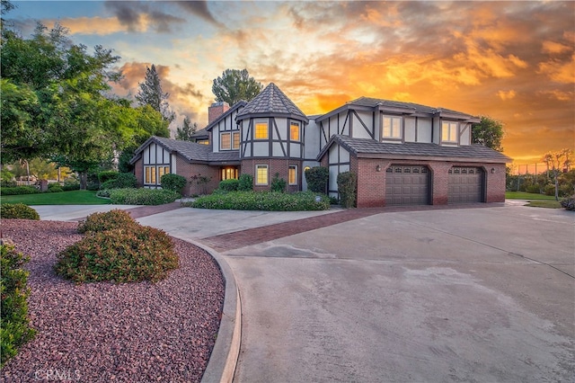 6735 Calais Ct, Riverside, CA 92506 - tudor house with brick siding, a chimney, concrete driveway, an attached garage, and stucco siding