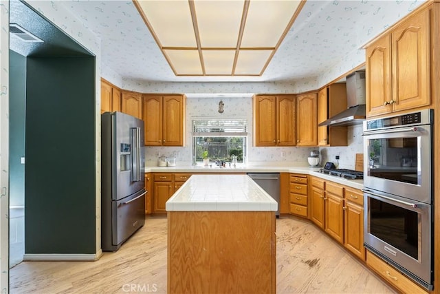32244 Corte Coronado, Temecula, CA 92592 - kitchen with stainless steel appliances, wall chimney exhaust hood, light wood-style floors, a kitchen island, and wallpapered walls