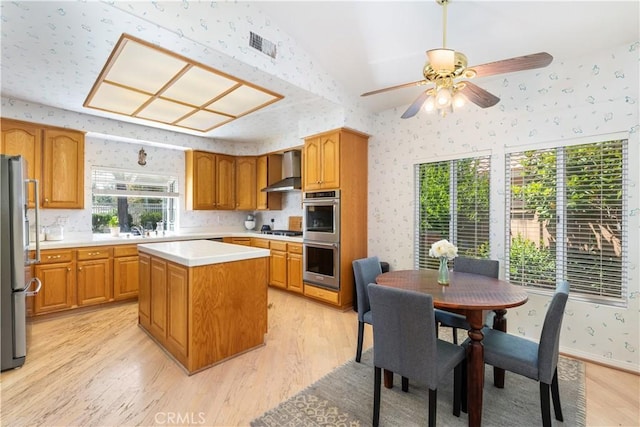 32244 Corte Coronado, Temecula, CA 92592 - kitchen featuring appliances with stainless steel finishes, wallpapered walls, wall chimney exhaust hood, light wood finished floors, and light countertops