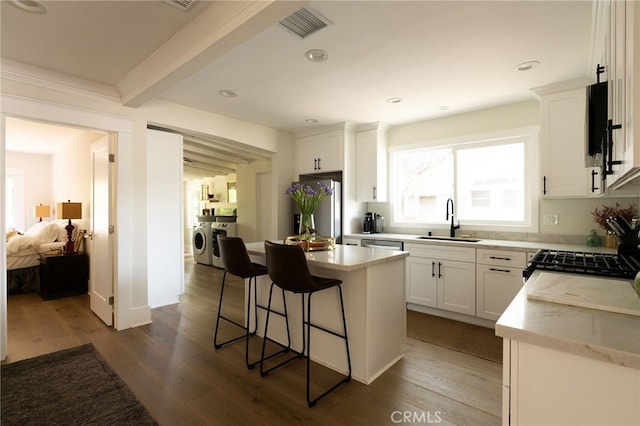 814 E Foothill Blvd, Monrovia, CA 91016 - kitchen featuring washing machine and clothes dryer, freestanding refrigerator, a kitchen bar, dark wood-type flooring, and a kitchen island