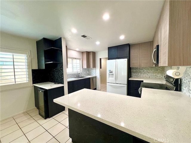 42915 Wisconsin Ave, Palm Desert, CA 92211 - kitchen featuring stainless steel appliances, backsplash, a peninsula, light stone countertops, and light tile patterned floors