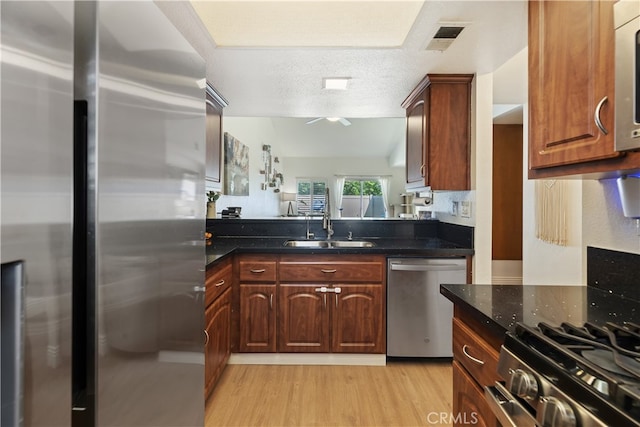 1103 Stone Pine Ln Unit C, Corona, CA 92879 - kitchen featuring appliances with stainless steel finishes, light wood-style flooring, dark stone counters, and a textured ceiling