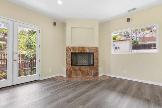 9915 Jacoby Rd, Spring Valley, CA 91977 - unfurnished living room featuring wood finished floors, healthy amount of natural light, french doors, a tiled fireplace, and recessed lighting
