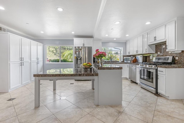 9915 Jacoby Rd, Spring Valley, CA 91977 - kitchen with appliances with stainless steel finishes, ornamental molding, white cabinets, tasteful backsplash, and a center island