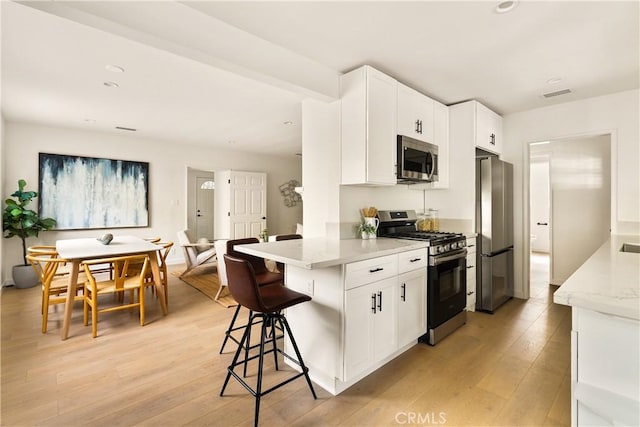14519 Addison, Sherman Oaks, CA 91403 - kitchen with appliances with stainless steel finishes, light wood-type flooring, white cabinets, a kitchen bar, and recessed lighting