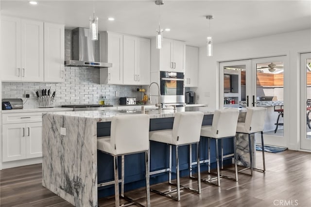 1954 Shipway Ave, Long Beach, CA 90815 - kitchen with wall chimney range hood, decorative backsplash, dark wood-style floors, a kitchen island with sink, and white cabinets