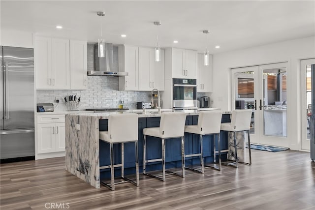 1954 Shipway Ave, Long Beach, CA 90815 - kitchen with stainless steel appliances, wall chimney range hood, an island with sink, dark wood-style floors, and white cabinetry