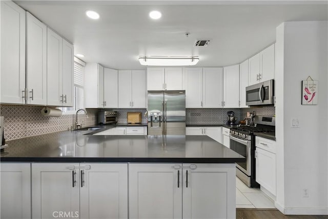 11445 Moorpark St Unit 12, Studio City, CA 91602 - kitchen featuring appliances with stainless steel finishes, dark countertops, a peninsula, white cabinets, and recessed lighting