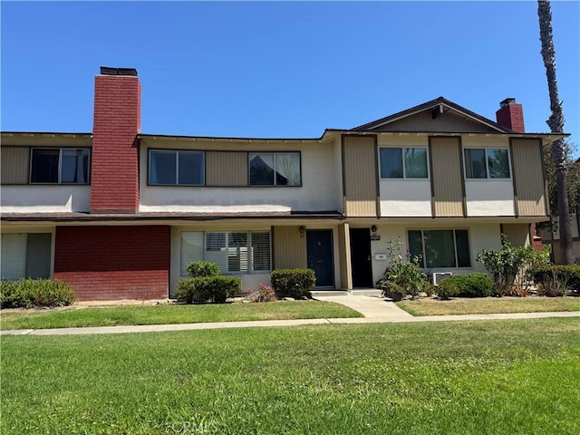 1722 Mitchell Ave Unit 123, Tustin, CA 92780 - townhome / multi-family property with a chimney, a front lawn, brick siding, and stucco siding