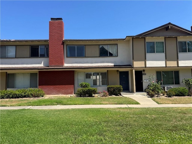 1722 Mitchell Ave Unit 123, Tustin, CA 92780 - view of property featuring a chimney, a front lawn, brick siding, and stucco siding
