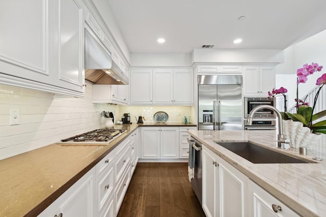 196 Coral Cove Way, Encinitas, CA 92024 - kitchen with stainless steel appliances, white cabinetry, light stone countertops, dark wood-style flooring, and decorative backsplash