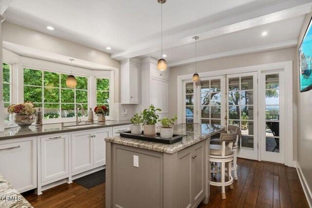 320 N San Rafael Ave, Pasadena, CA 91105 - kitchen featuring dark wood finished floors, white cabinetry, healthy amount of natural light, beam ceiling, and a kitchen breakfast bar