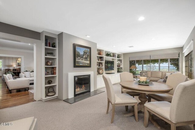 320 N San Rafael Ave, Pasadena, CA 91105 - dining space with light carpet, a glass covered fireplace, recessed lighting, built in shelves, and crown molding
