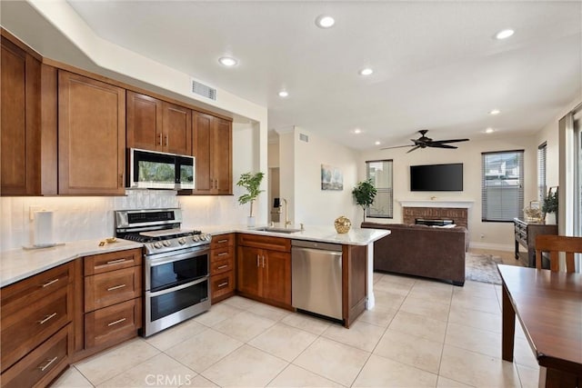 36 Via Tronido, Rancho Santa Margarita, CA 92688 - kitchen with stainless steel appliances, ceiling fan, a peninsula, decorative backsplash, and a fireplace